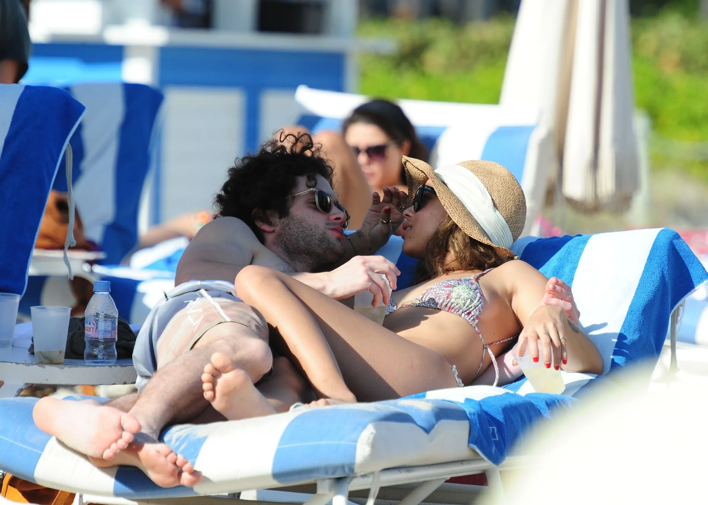 Penn Badgley and Zoe Kravitz relaxing on lounge chairs on Miami Beach.