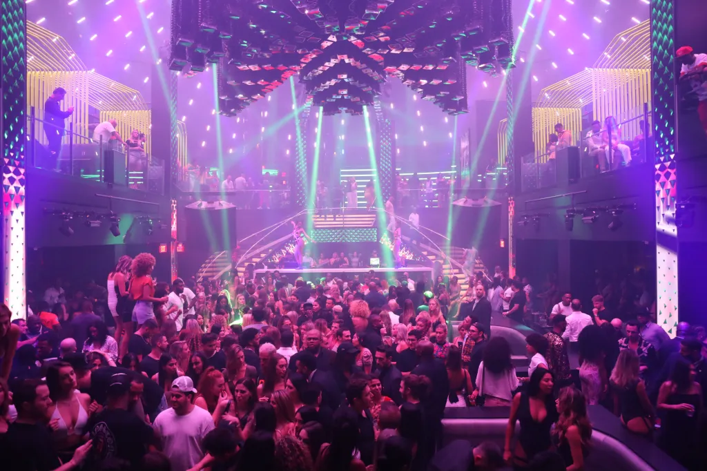LIV Miami nightclub with a crowd of people and laser lights.