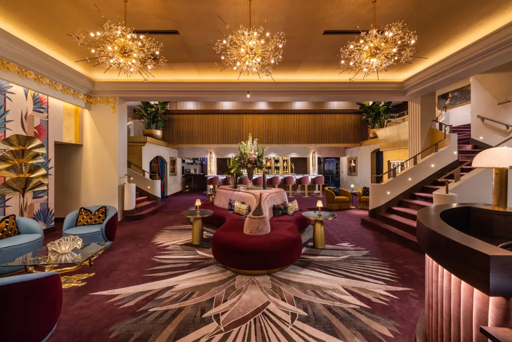 Luxurious and modern hotel lobby with ornate chandeliers, a bar, and a grand staircase.