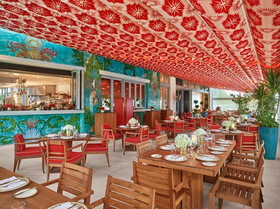 Outdoor restaurant patio with red chairs and a red and white patterned ceiling.