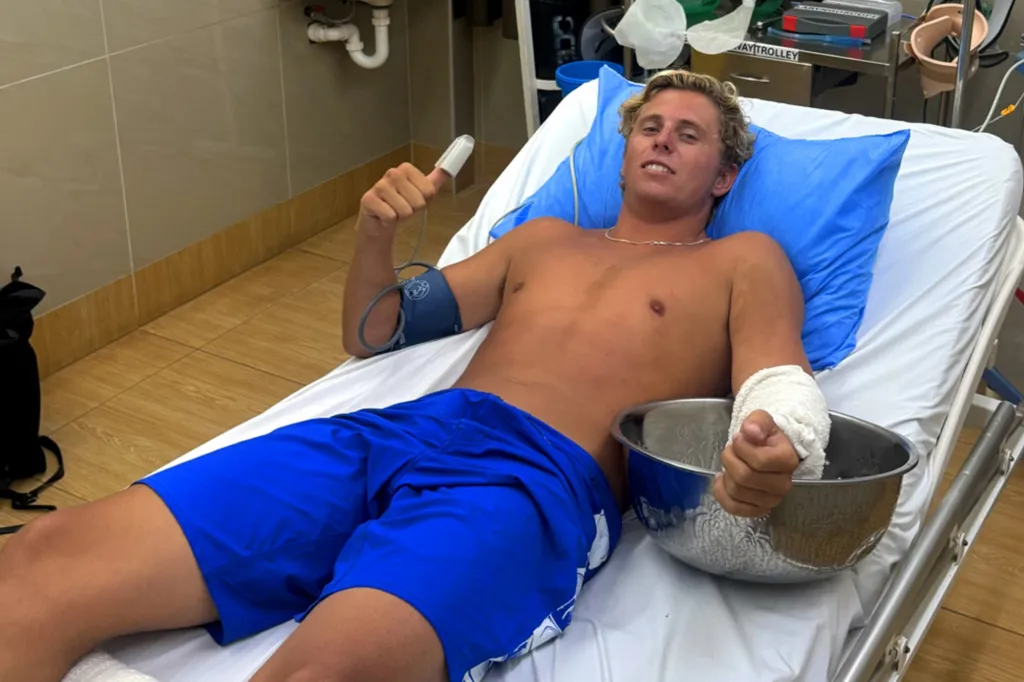 Australian surfer Guy Rowles in a hospital bed with a bandaged hand.