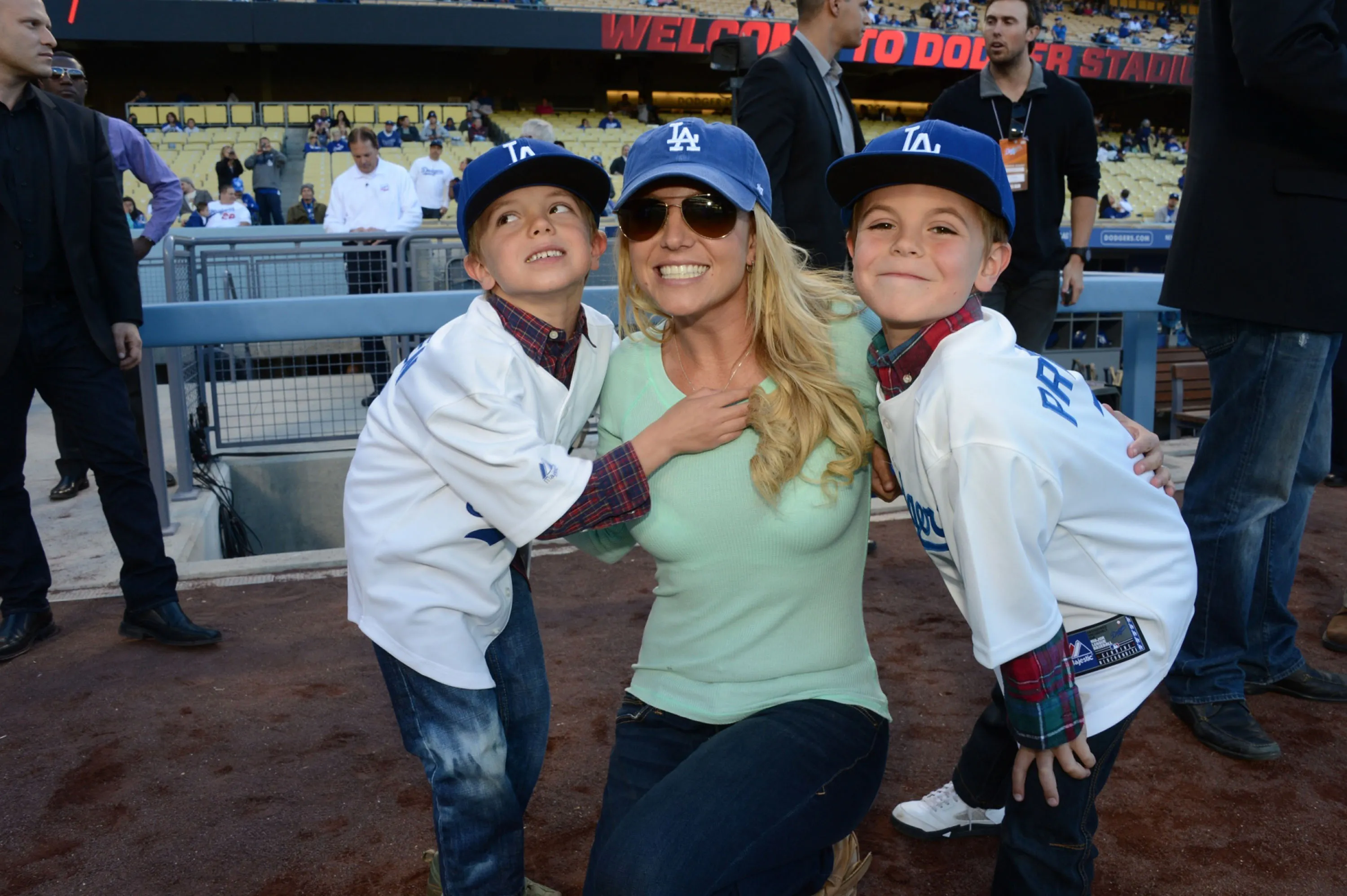 Britney Spears kneeling with her sons, Jayden James Federline and Sean Preston Federline, who are both wearing LA Dodgers jerseys and hats.