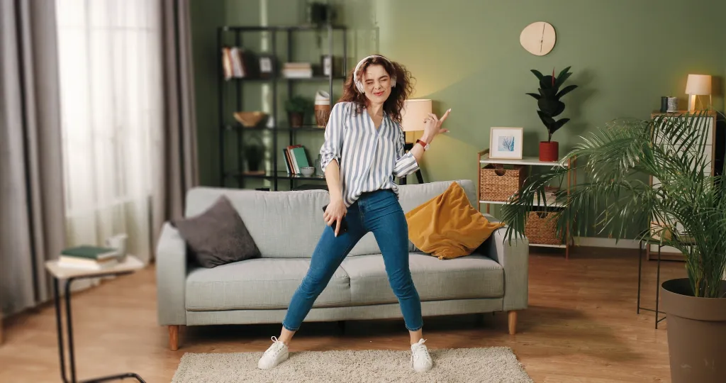 Young Caucasian woman dancing and jumping in headphones.