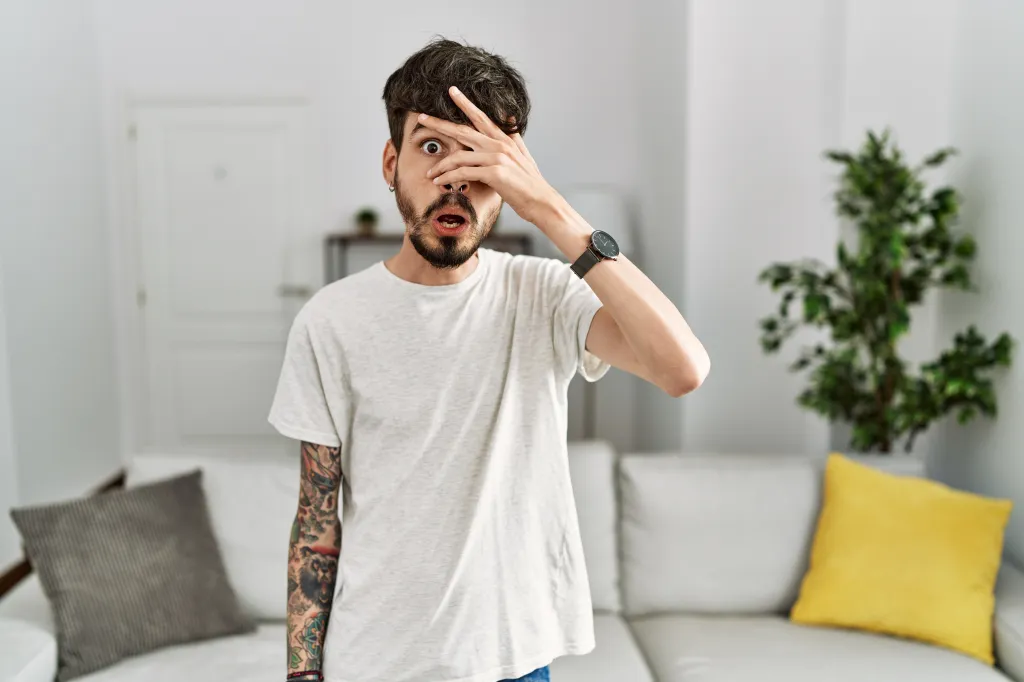 Man peeking between his fingers. 