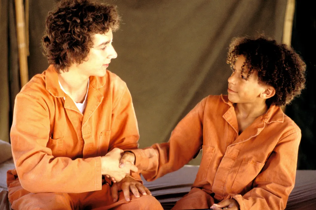 Shia LaBeouf and Khleo Thomas shaking hands in orange uniforms from the movie "Holes."