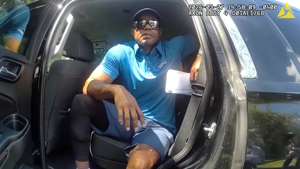 Golfer Tiger Woods sitting in an unmarked police vehicle after a car crash.