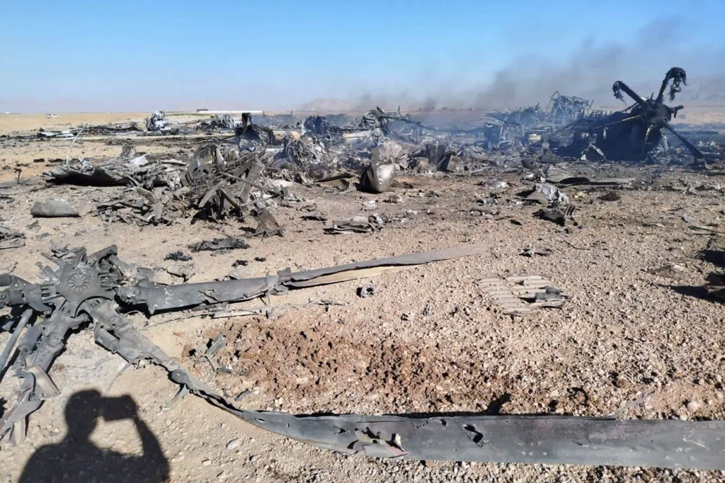 Wreckage of a downed American transport plane and two helicopters in the desert.