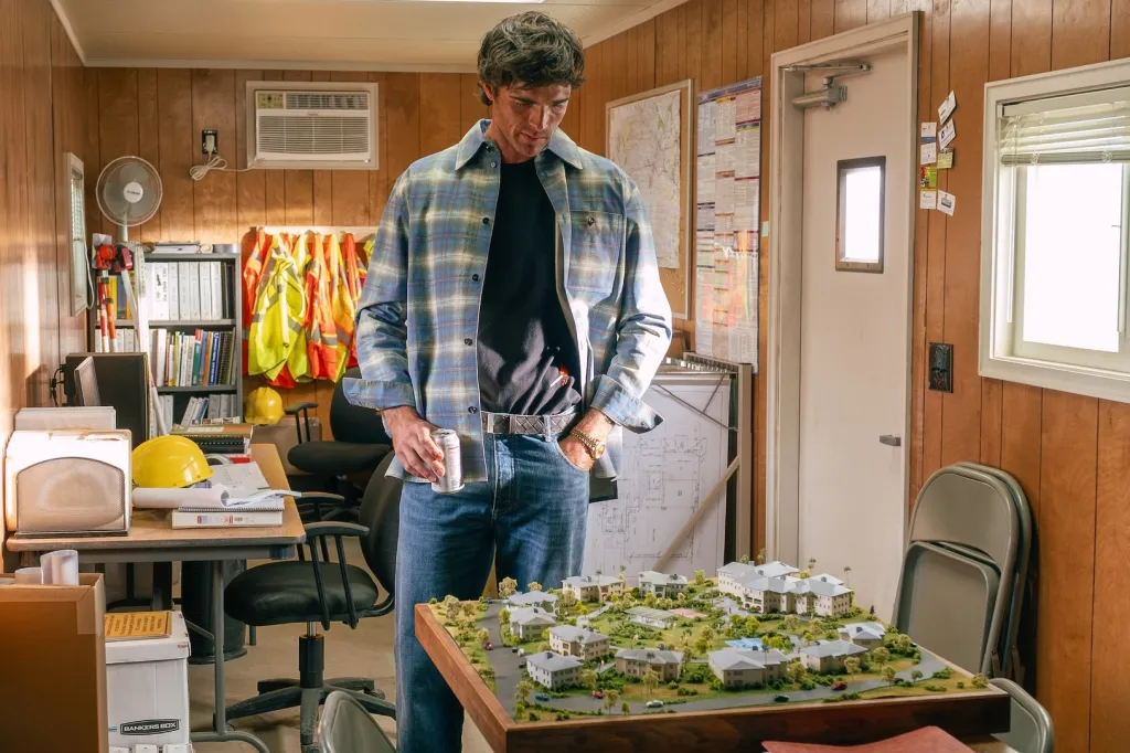 Jacob Elordi from the series "Euphoria" standing next to a model housing development.