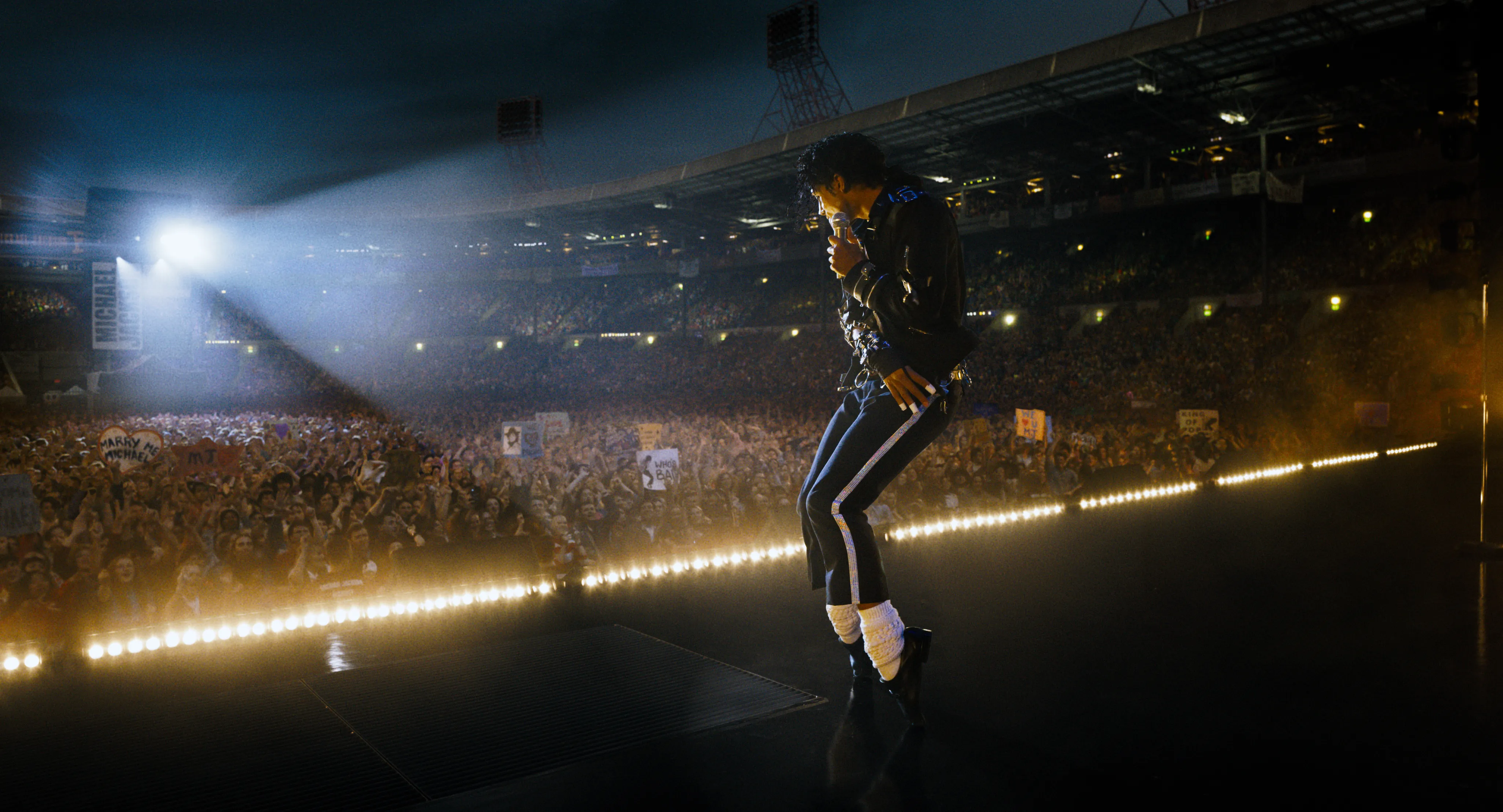 Jaafar Jackson as Michael Jackson on stage performing for a large crowd in a stadium.