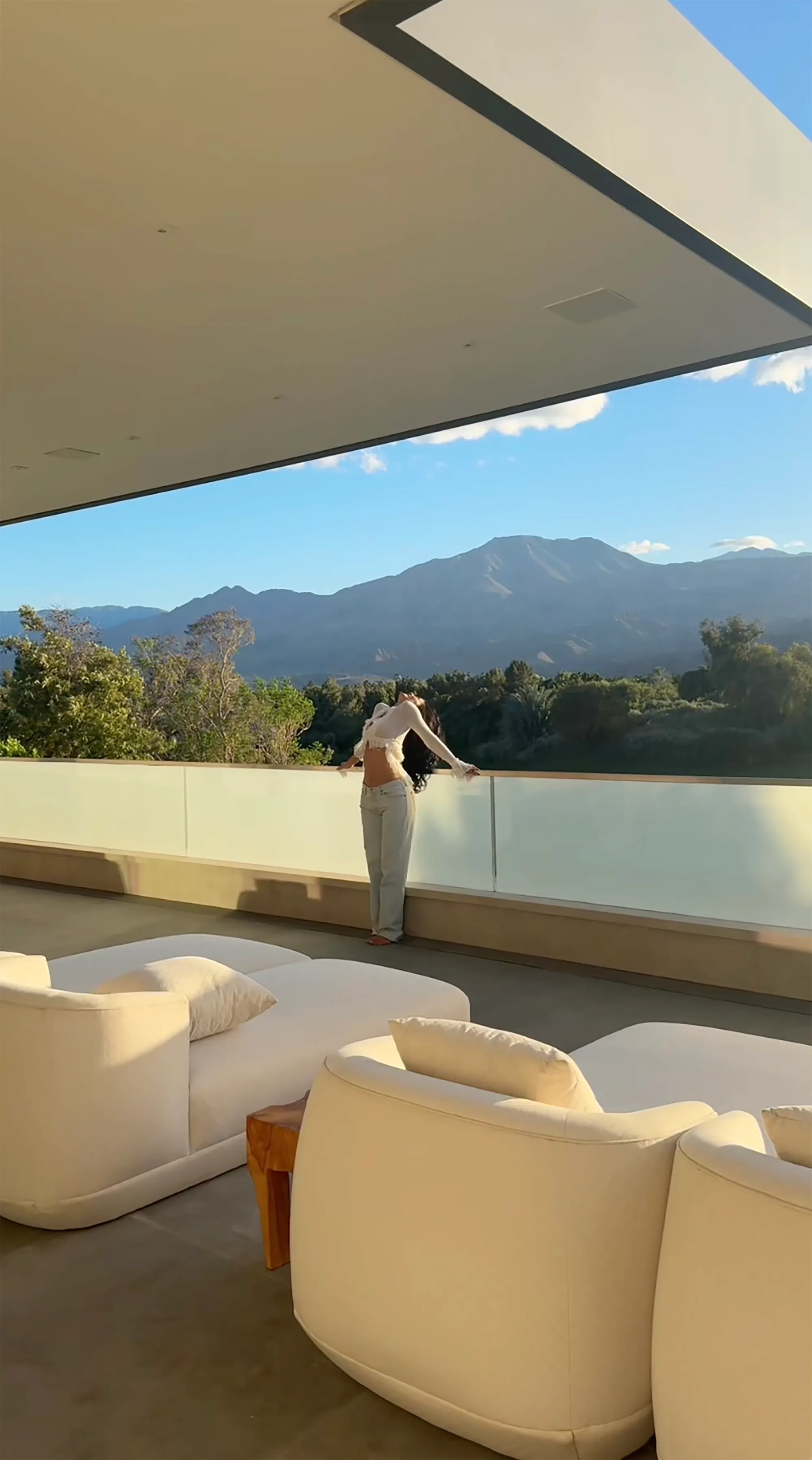 Kylie Jenner standing on a balcony with a mountain view.