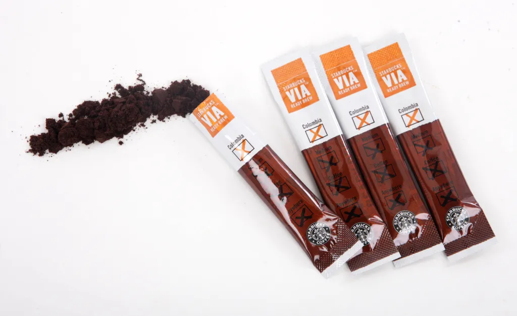 Starbucks VIA Ready Brew instant coffee packets, with coffee grounds spilled from one packet.