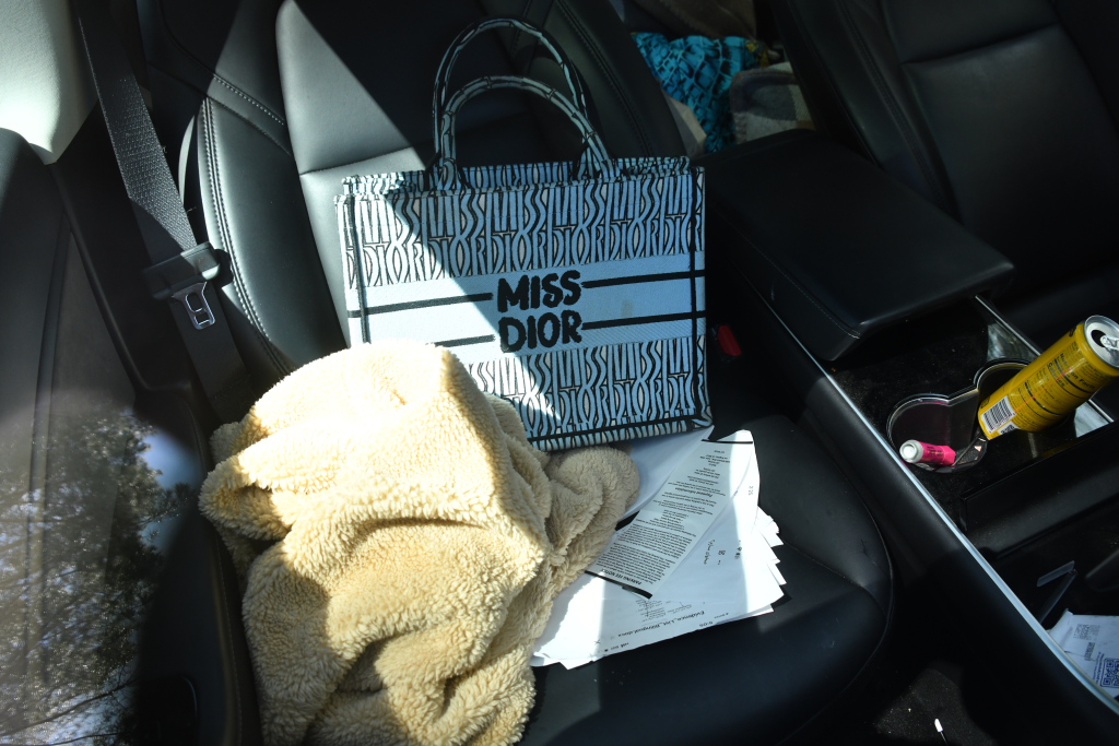 The interior of the abandoned car of Sarinasadat Hosseiny containing a "MISS DIOR" tote bag, a furry blanket, documents, and an open soda can.
