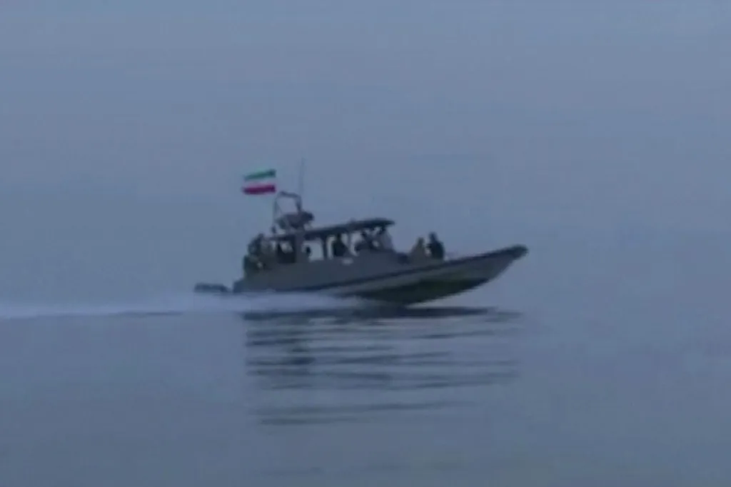 An Iranian Revolutionary Guards boat with an Iranian flag on its stern speeds across the water.