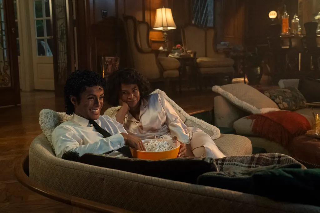 Jaafar Jackson as Michael Jackson and Nia Long as Katherine Jackson watch a movie together on a sofa.