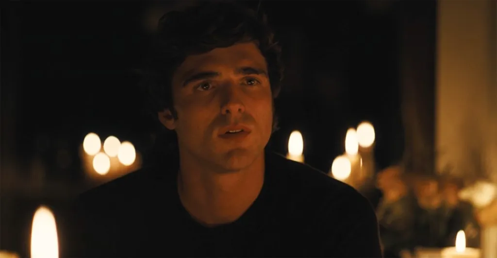 Jacob Elordi as Nate Jacobs looking forward at a table lit by candles.