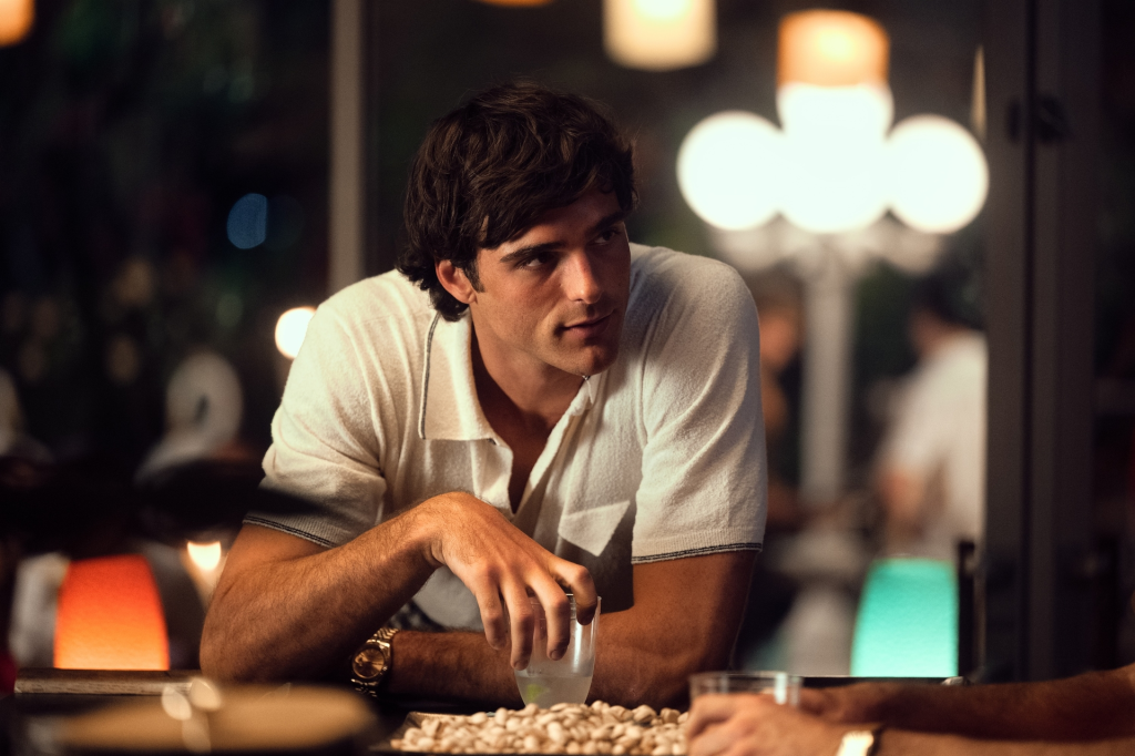 Jacob Elordi from "Euphoria" wearing a white shirt and holding a drink.