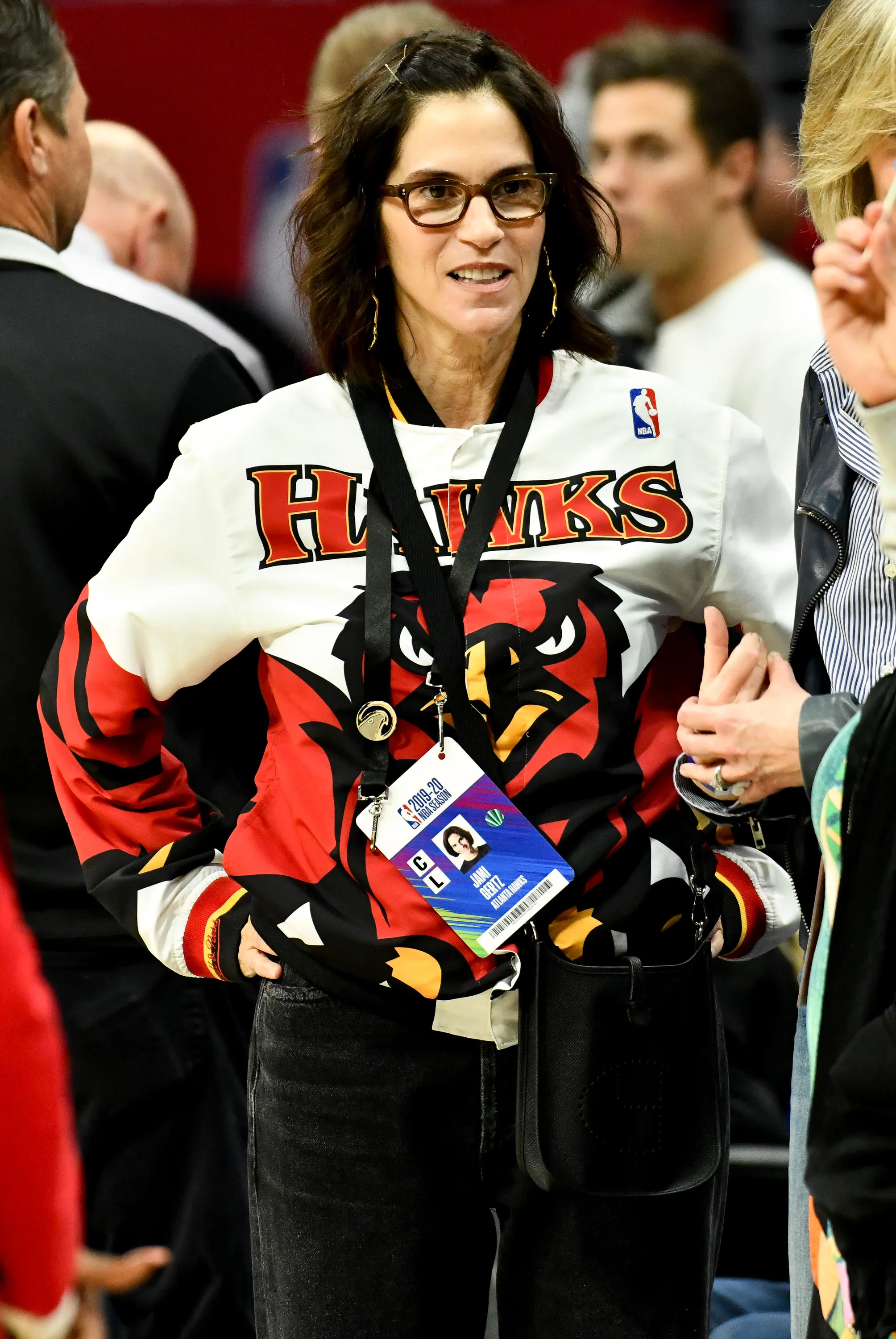 Jami Gertz attending a basketball game, wearing a jacket with a Hawks logo.