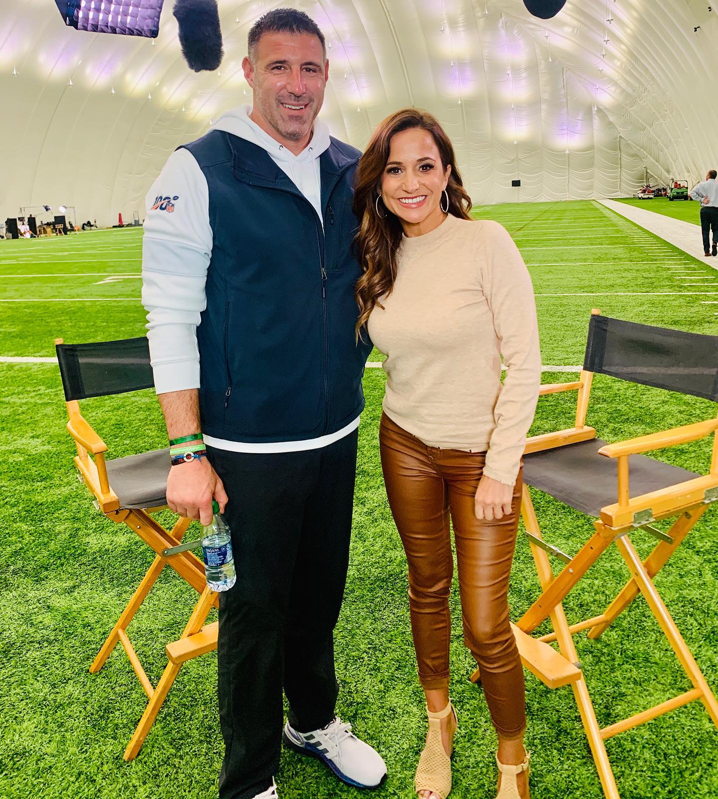 Mike Vrabel and Dianna Russini posing on a football field.