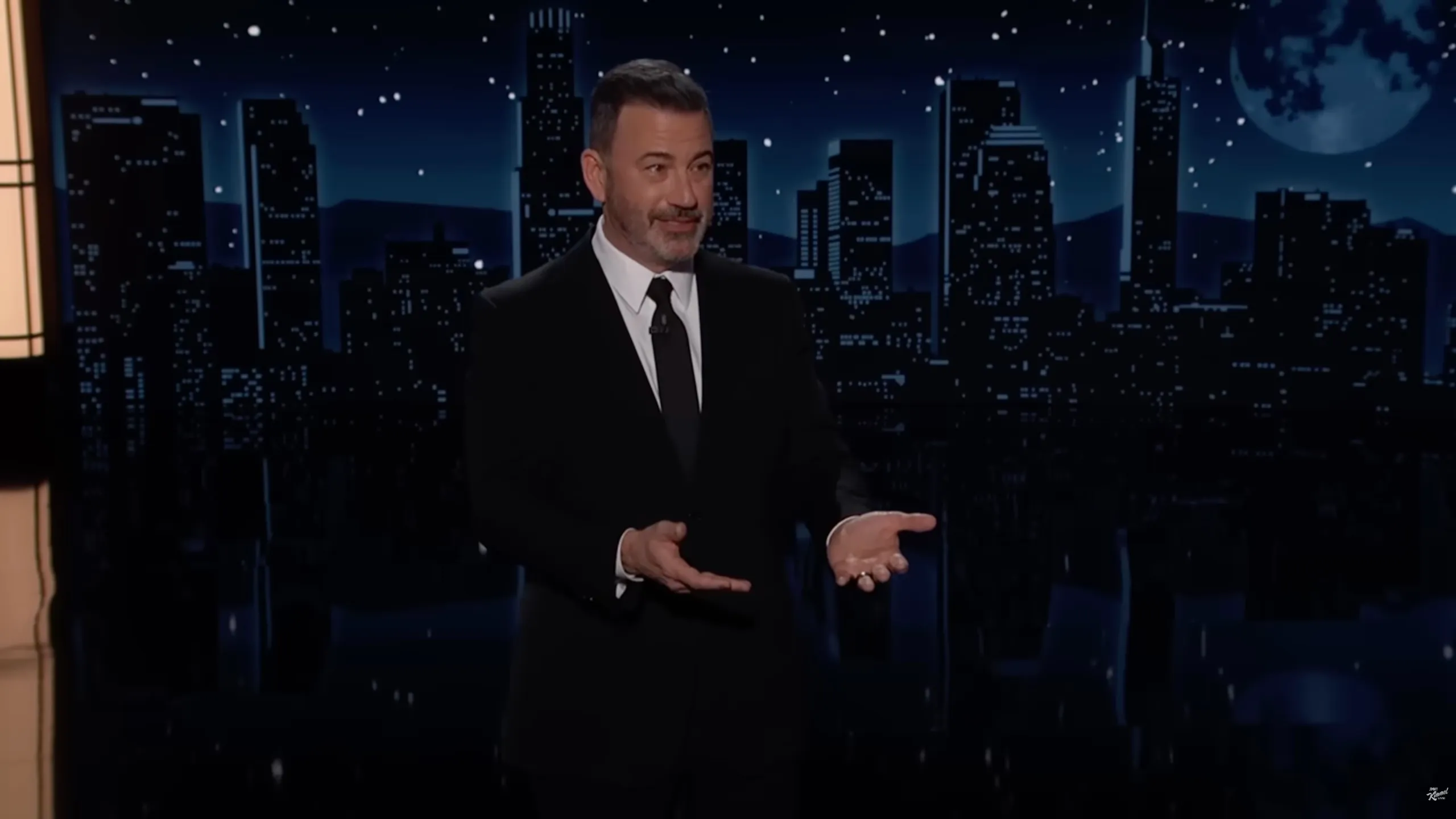 Jimmy Kimmel on a stage with a cityscape backdrop.