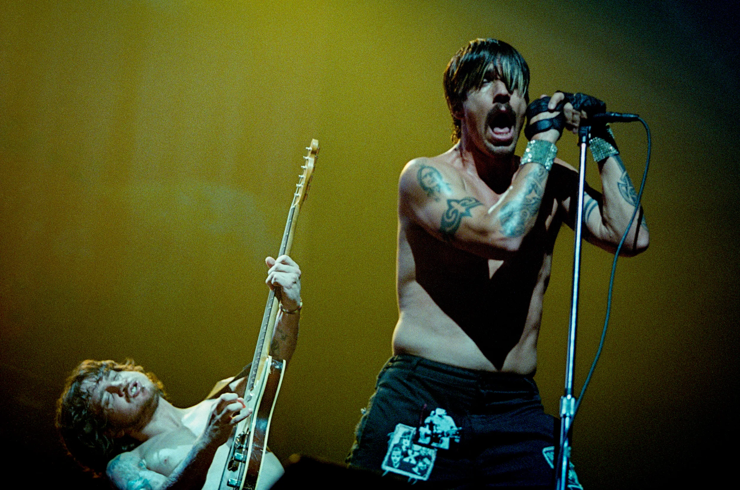 John Frusciante and Anthony Kiedis performing on stage with Red Hot Chili Peppers.