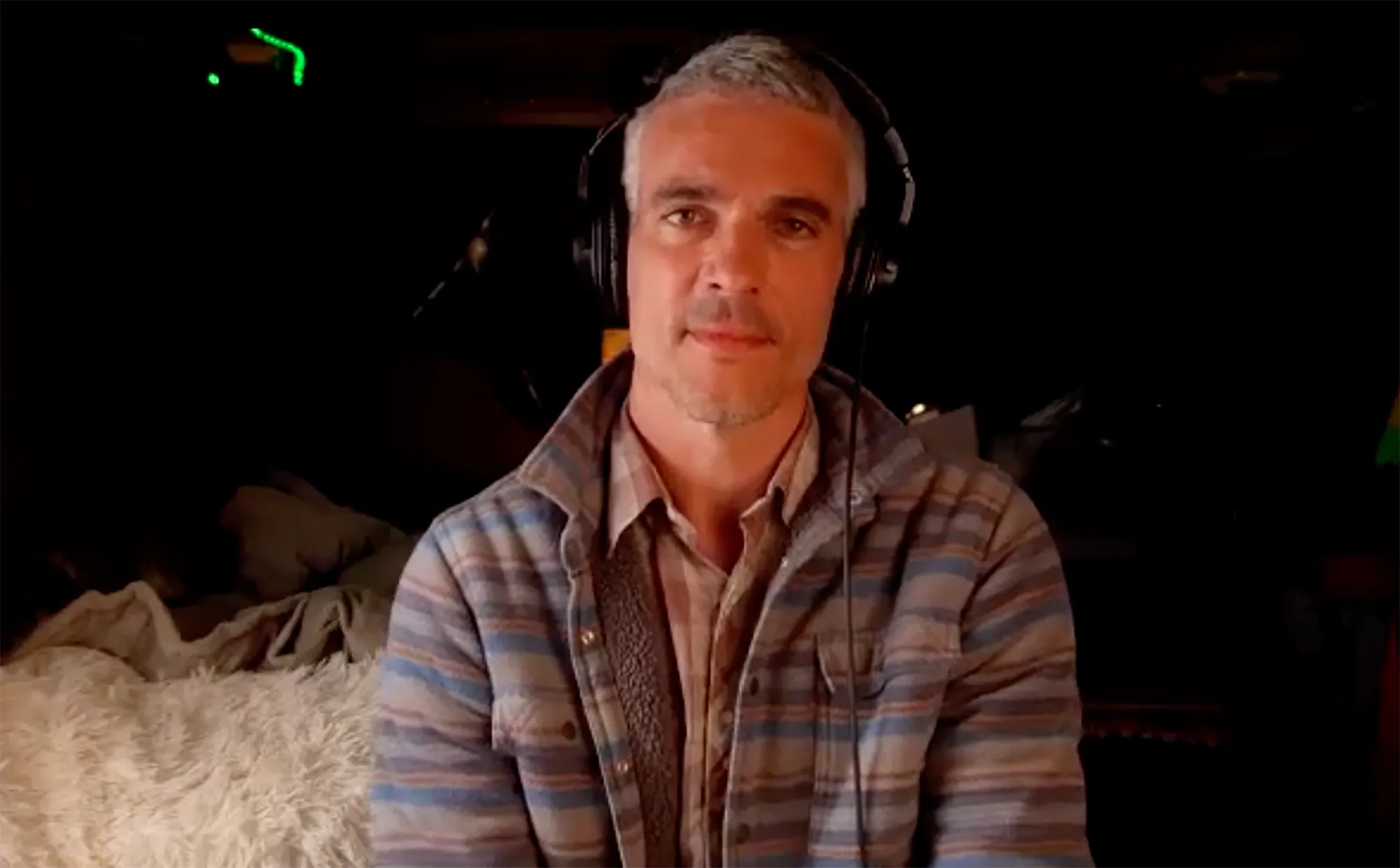 Josh Kloss wearing headphones and a plaid jacket.