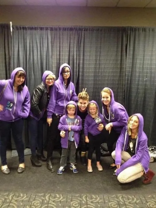 Katy Perry, Justin Bieber, and others pose in purple hoodies.