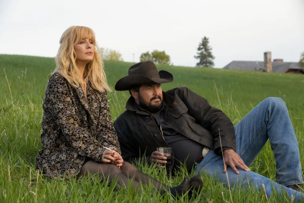 Kelly Reilly and Cole Hauser sitting in a field on Yellowstone.