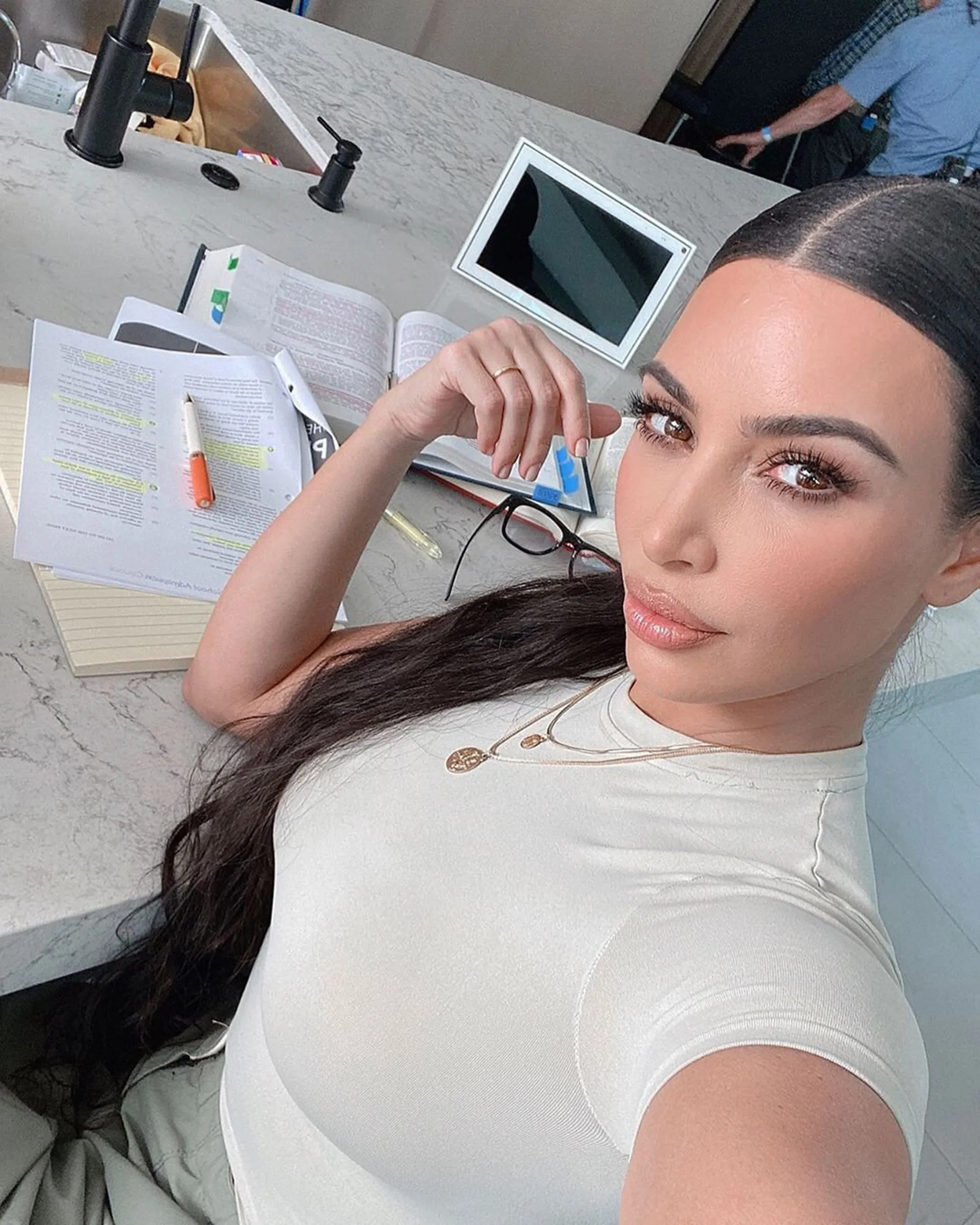 Kim Kardashian takes a selfie while studying law books.