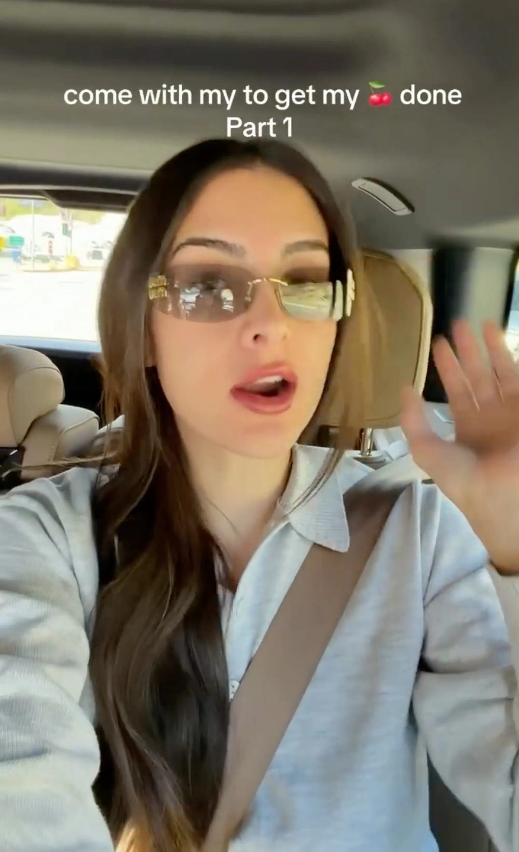Sophia Umansky in a car, wearing a light gray long-sleeved shirt and sunglasses, caption reads "come with my to get my 🍒 done Part 1"