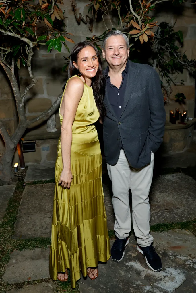 Meghan, Duchess of Sussex, in a chartreuse dress, and Ted Sarandos, in a navy blue blazer, blue shirt, and khaki pants, at Netflix's BEEF season 2 Montecito Tastemaker event.