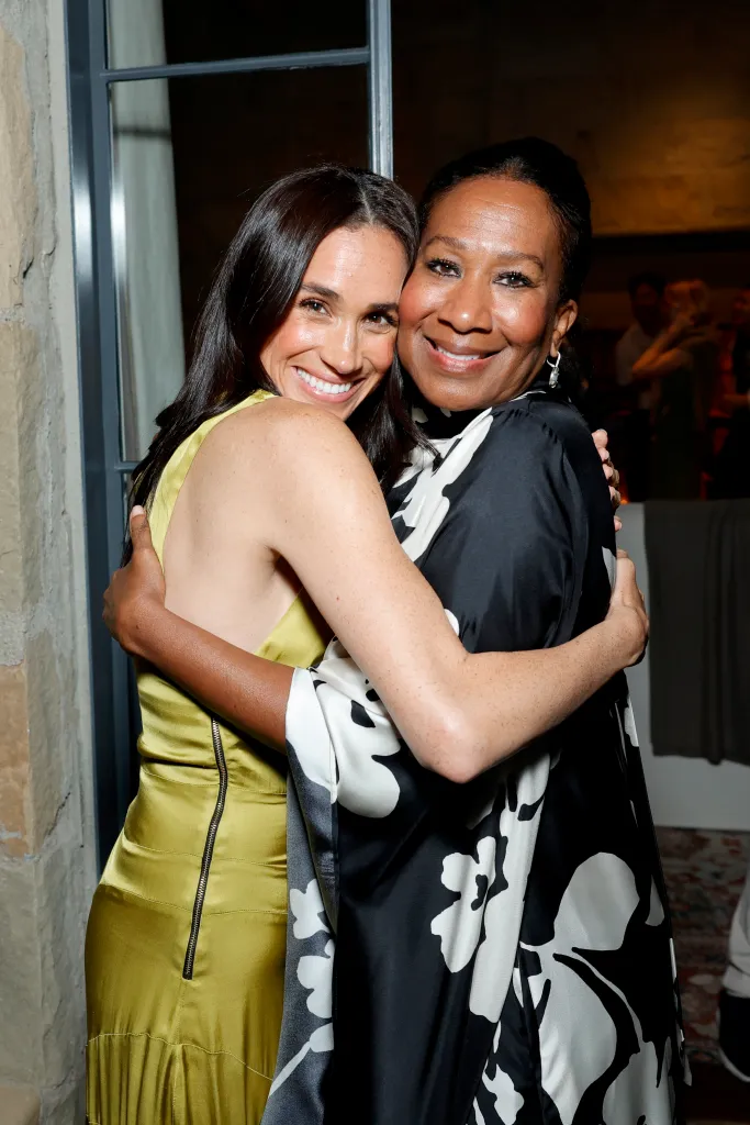 Meghan, Duchess of Sussex, in a chartreuse dress, and Nicole Avant, in a black and white patterned dress, embracing at Netflix's BEEF season 2 Montecito Tastemaker event.