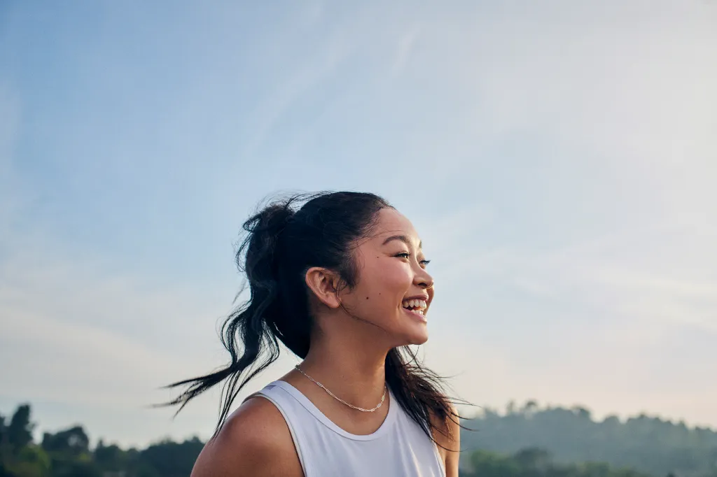 Lana Condor smiling in a white tank top.
