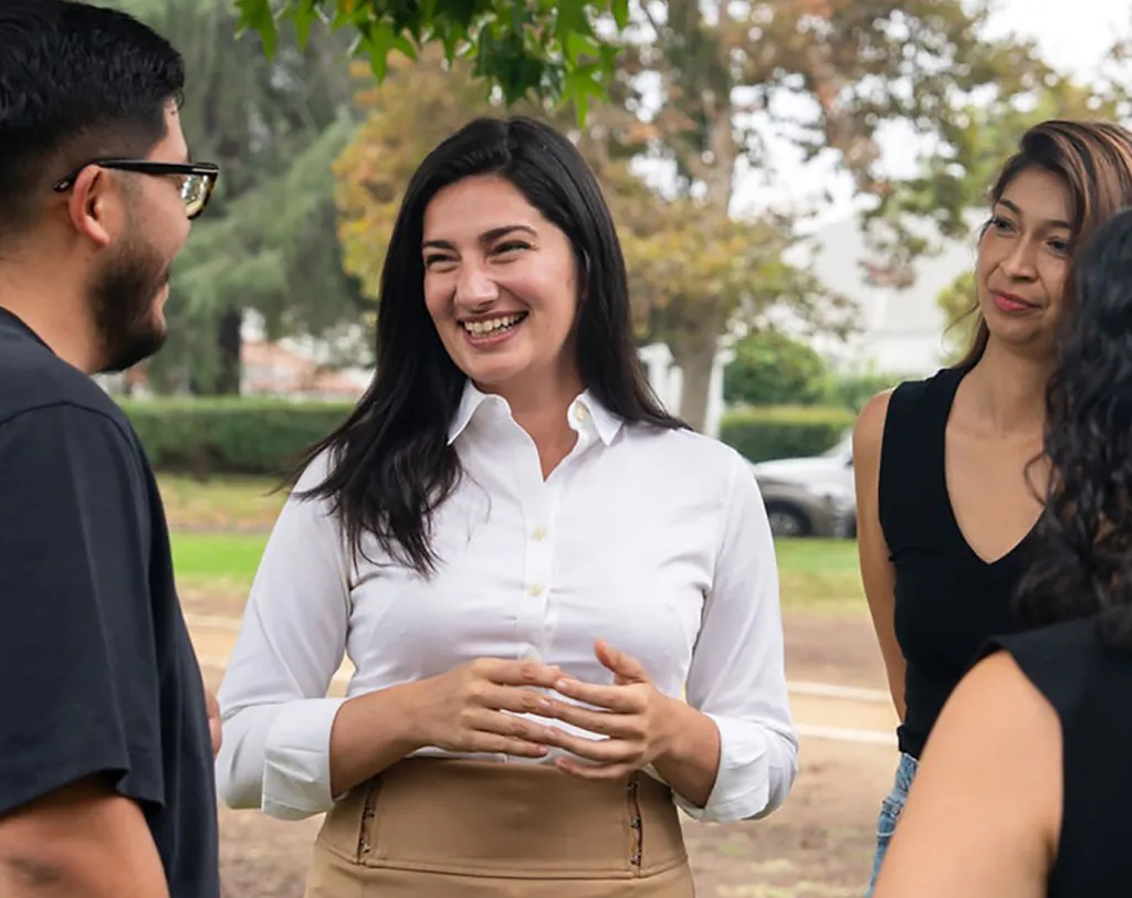 Marissa Roy smiling and talking with three other people outdoors.