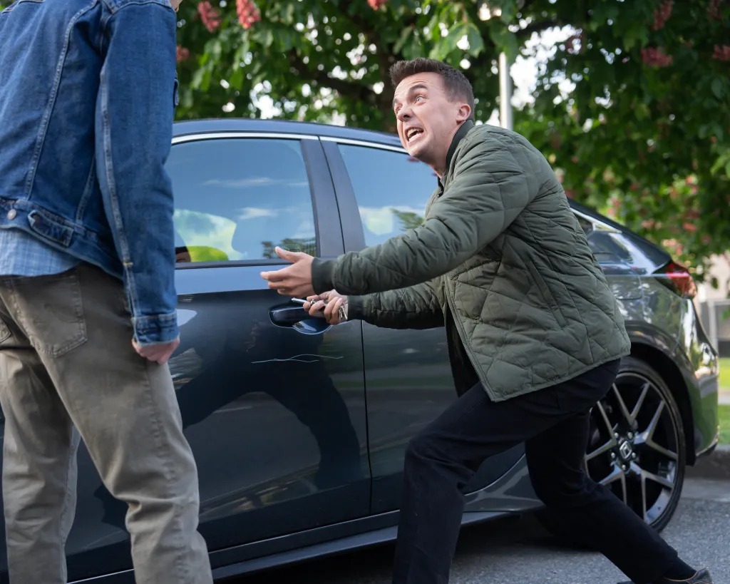 Frankie Muniz "keying" a car as another man in a denim jacket stands next to him.
