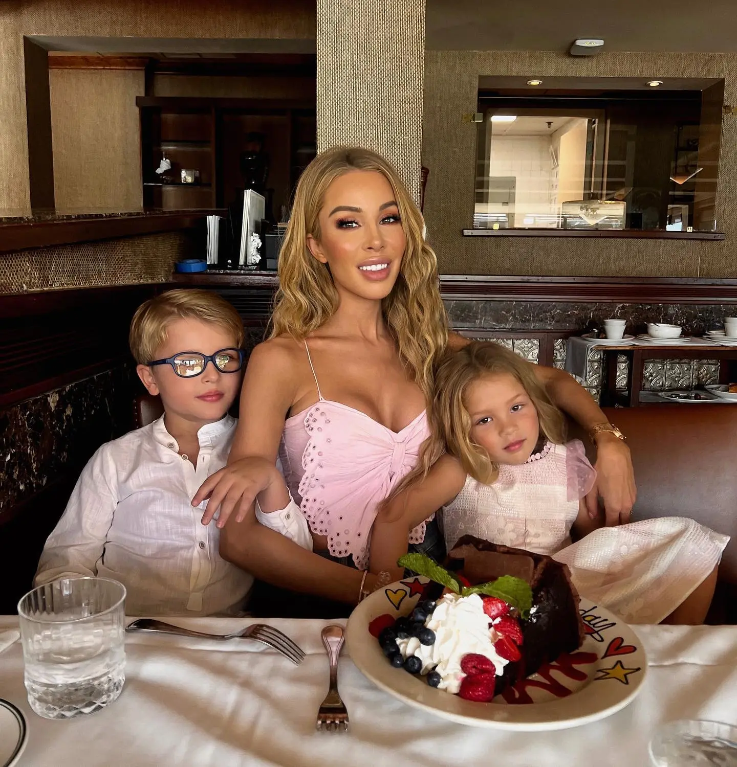 Lisa Hochstein posing with her two children and a slice of chocolate cake.