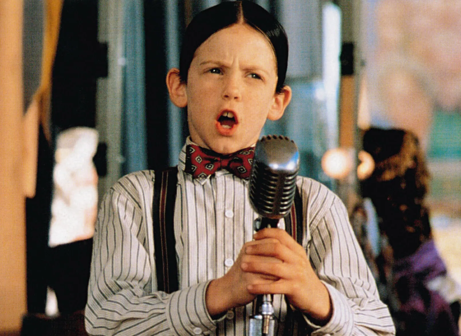 Bug Hall as Alfalfa, wearing a bowtie and suspenders, singing into a microphone in "The Little Rascals."