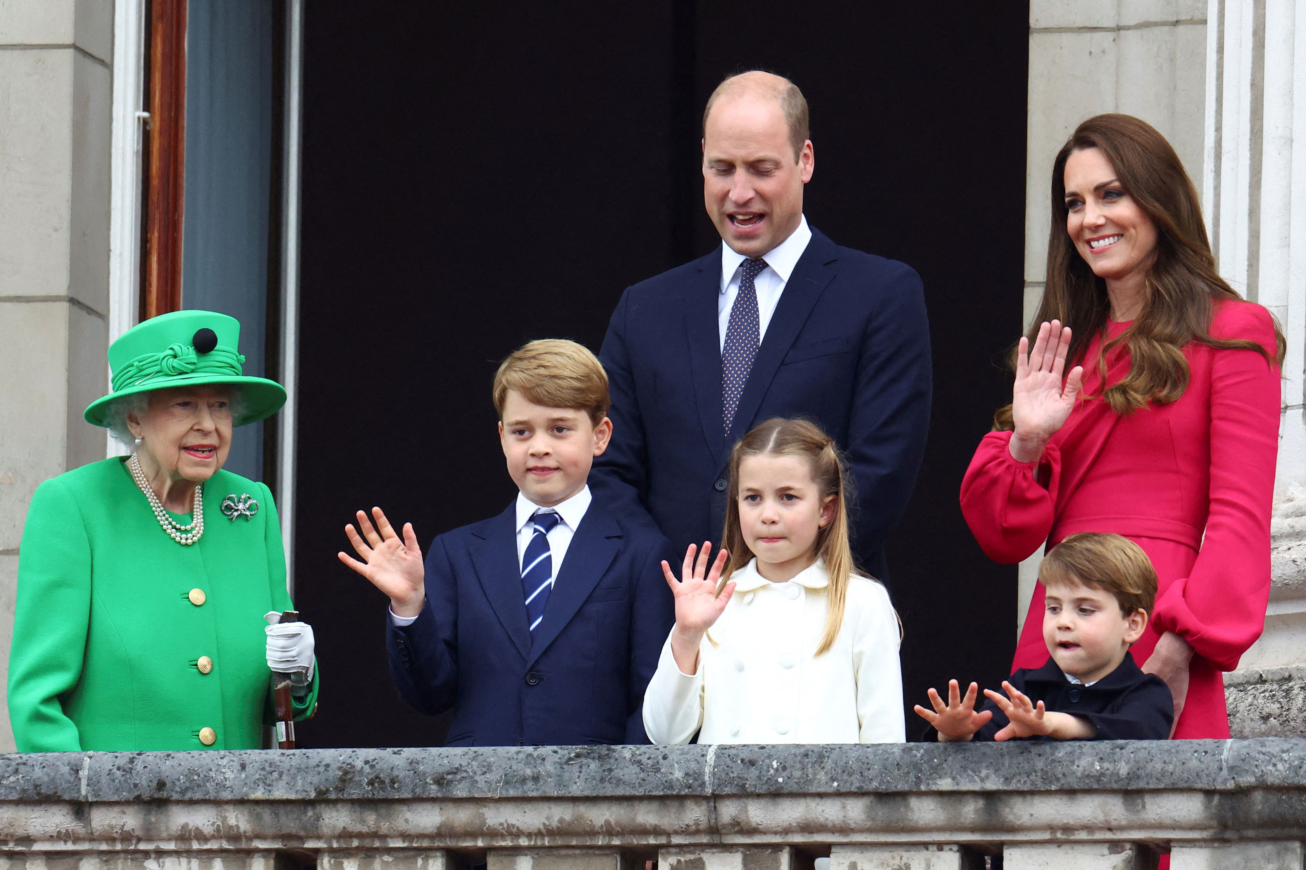 Queen Elizabeth II, Prince William, Catherine, Princess of Wales, and their three children wave from a balcony.