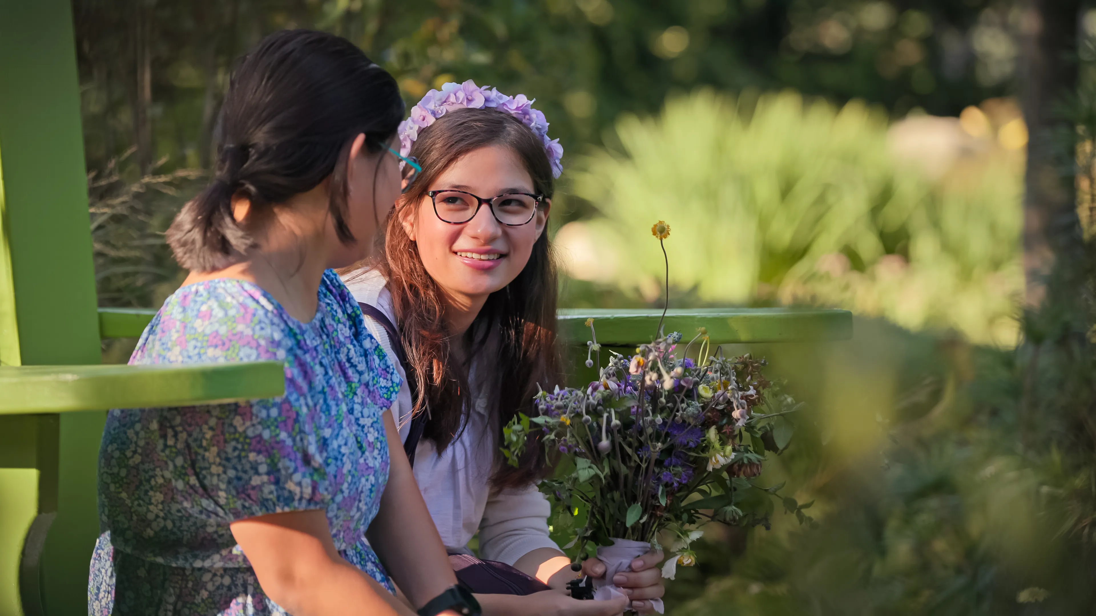 Peri from "Love on the Spectrum" looking at another woman, wearing a flower crown and holding a bouquet.