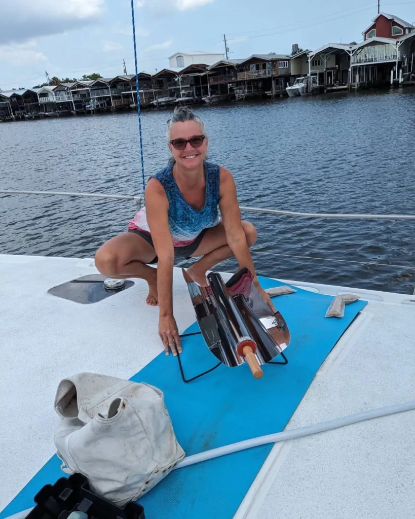 Lynette Hooker crouches beside a solar cooker on the deck of a boat.