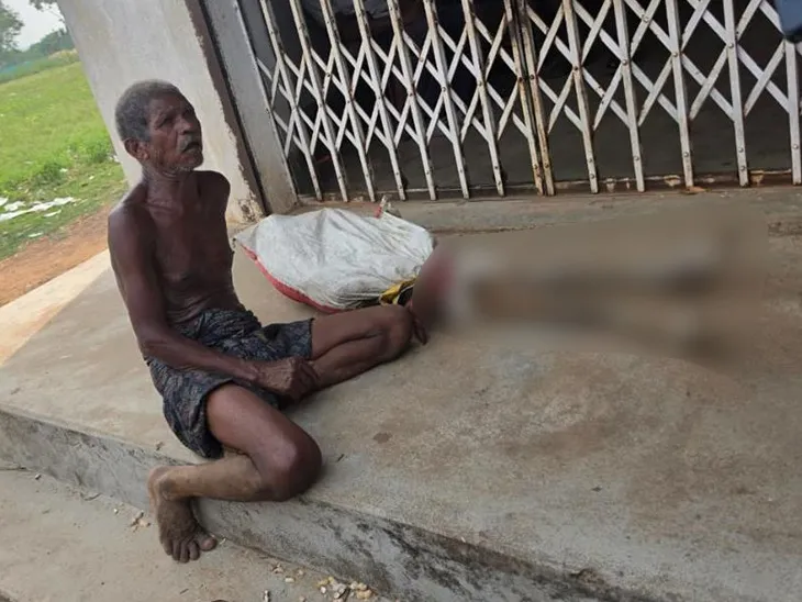 A man sits on a step next to a blurred object, which is identified in the caption as his dead sister's skeleton, outside a bank.