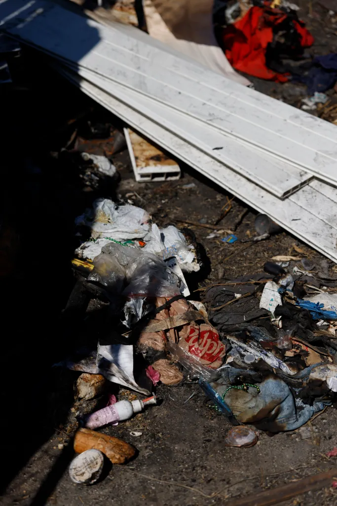 Trash and debris litter the ground next to a property that caught fire due to squatters.