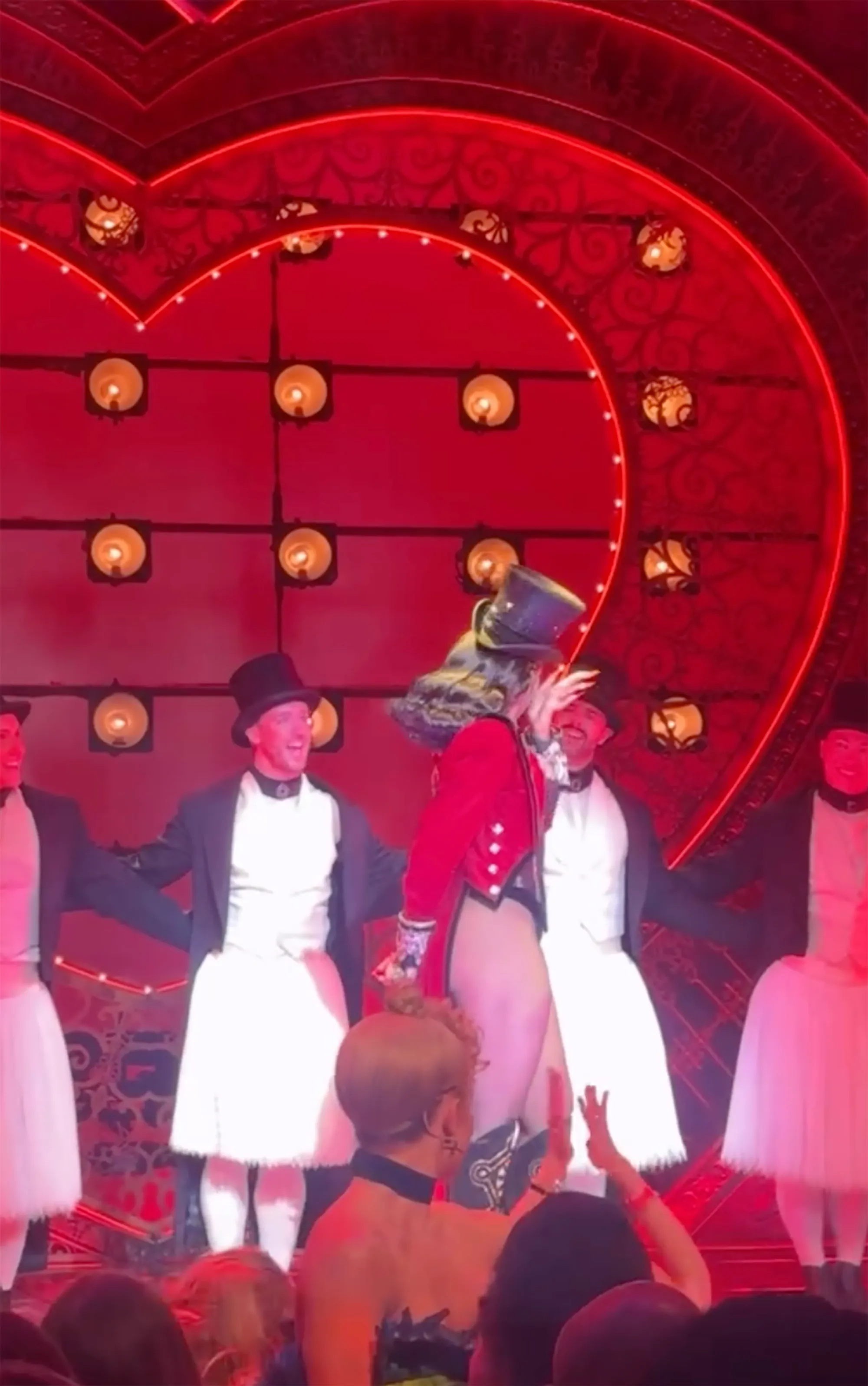 Megan Thee Stallion performing at a "Moulin Rouge" Broadway show, surrounded by male dancers, as she appears to cry.