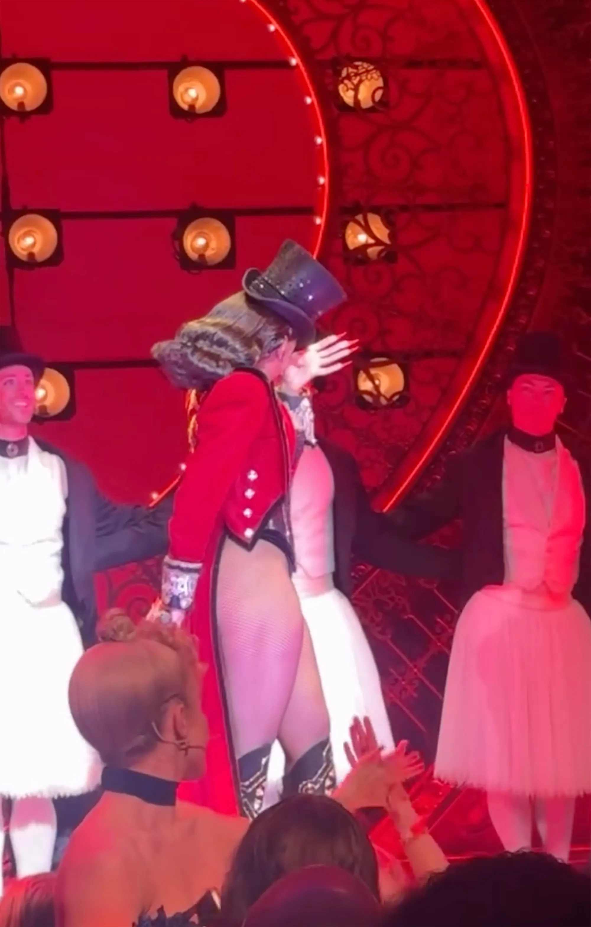 Megan Thee Stallion in a black top hat and red coat, wiping away tears on stage while performing as Zidler in "Moulin Rouge! The Musical".