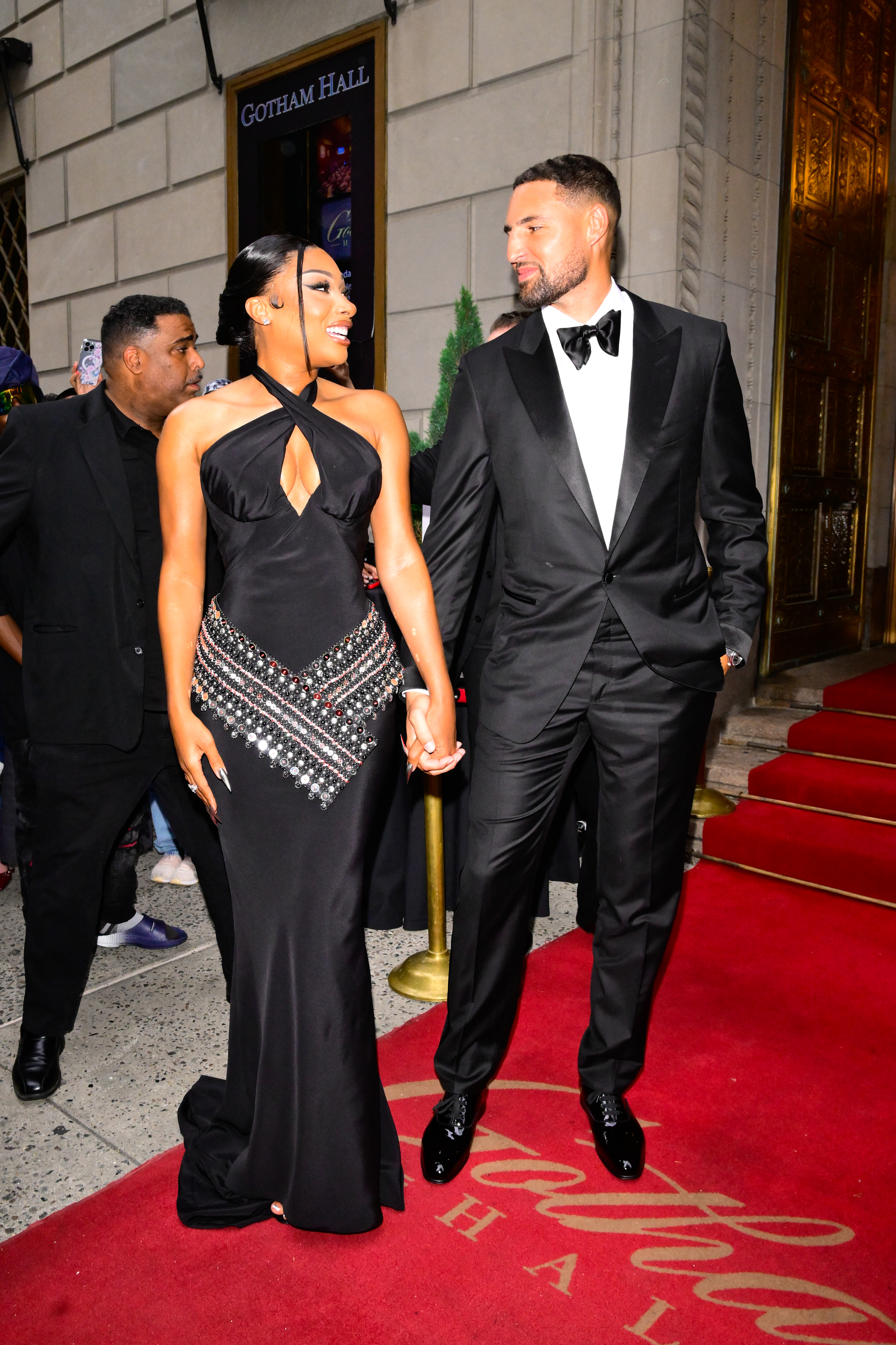 Megan Thee Stallion and Klay Thompson walk hand-in-hand on a red carpet.