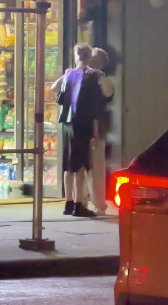 Meghan King Edmonds and Kyle Cooke kissing in front of a store at night.