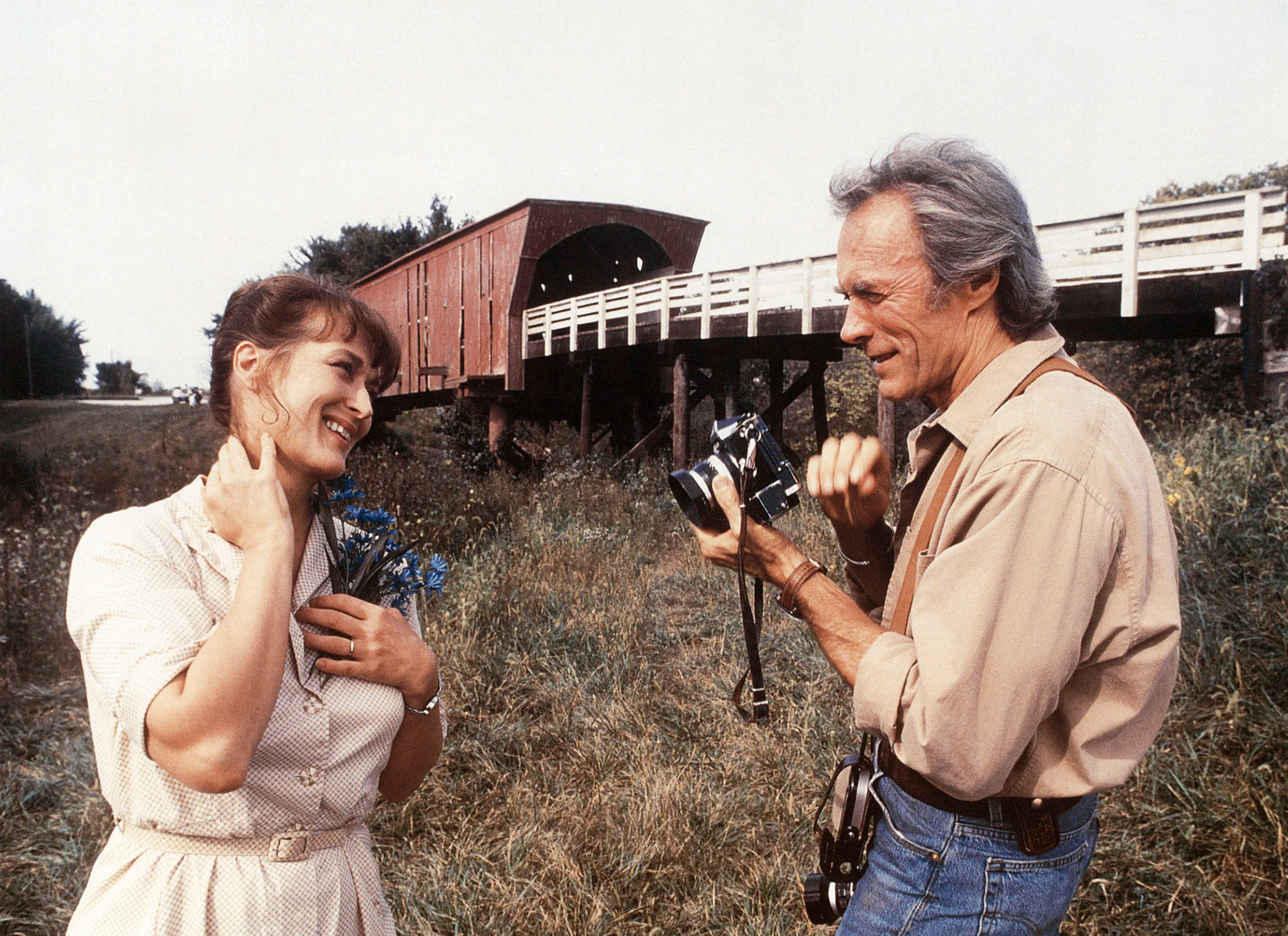 Clint Eastwood photographing Meryl Streep in front of a covered bridge in *The Bridges of Madison County*.