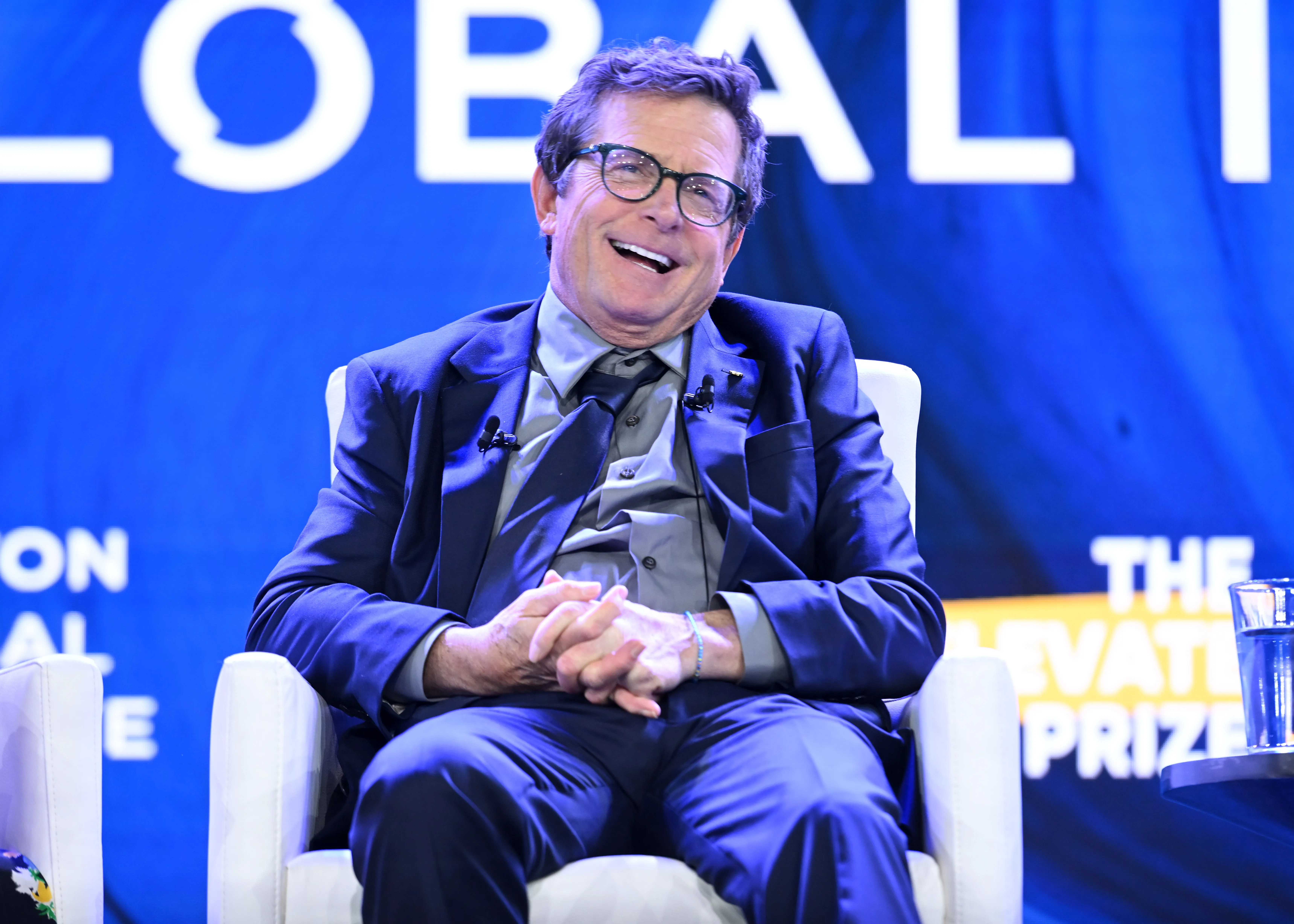 Michael J. Fox laughing while seated onstage.