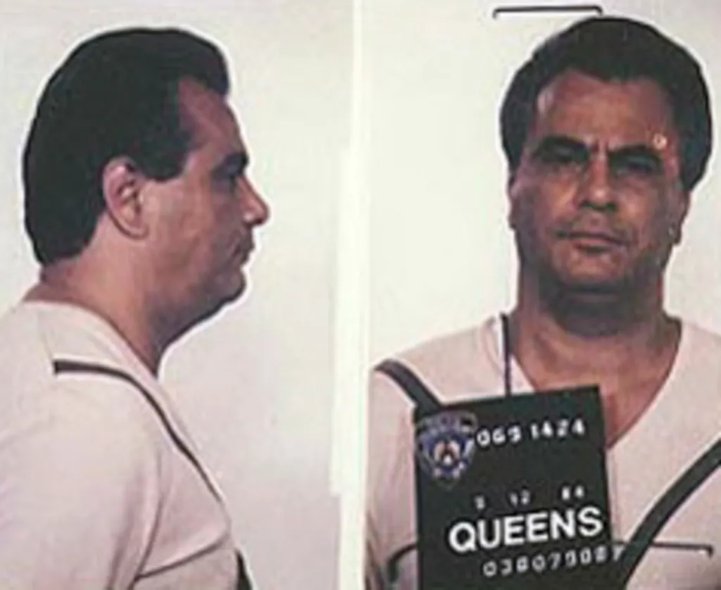 Mug shot of John Gotti, with a profile view on the left and a front-facing view on the right, holding a sign that says "QUEENS".