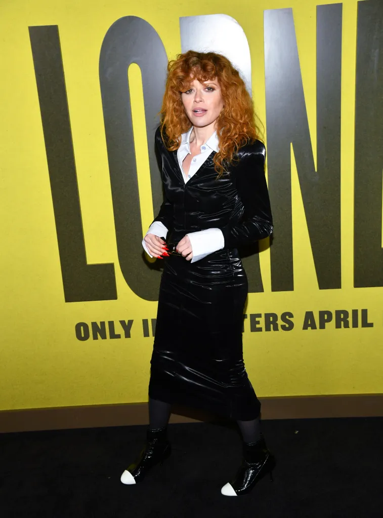 Natasha Lyonne poses in a black dress with white cuffs and black and white shoes at a film premiere.
