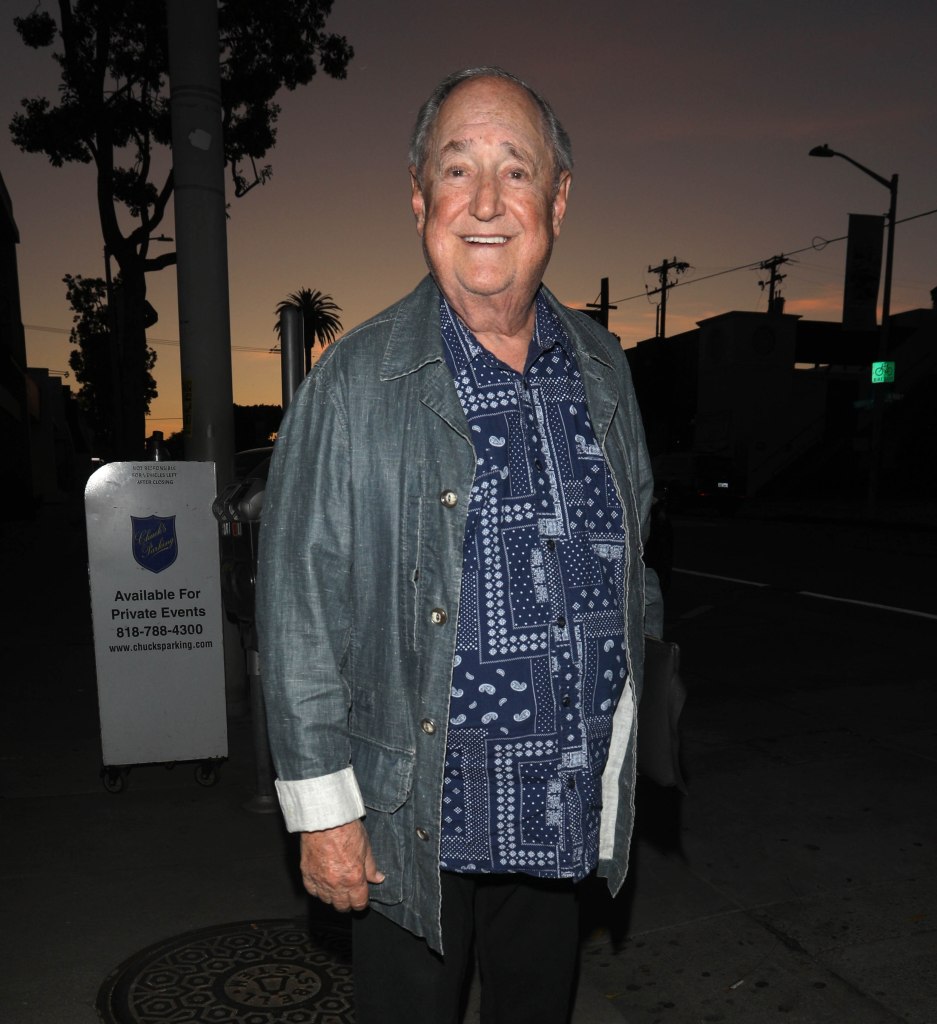 Neil Sedaka smiling at the camera outdoors at dusk.